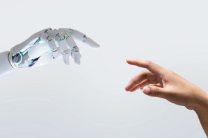 Foto de mão robótica representando a Inteligência artificial e uma mão humana
